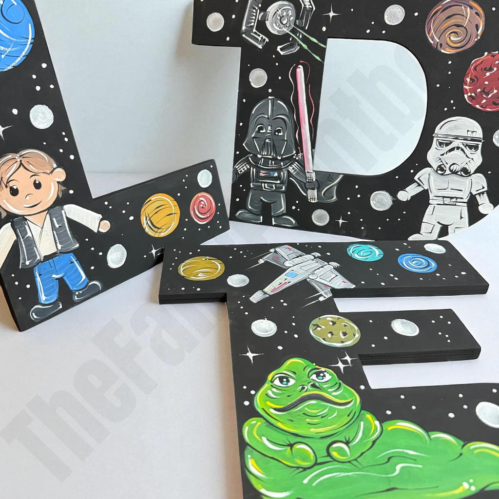 Set of baby jedi wood letters with colorful space-themed designs on a white background