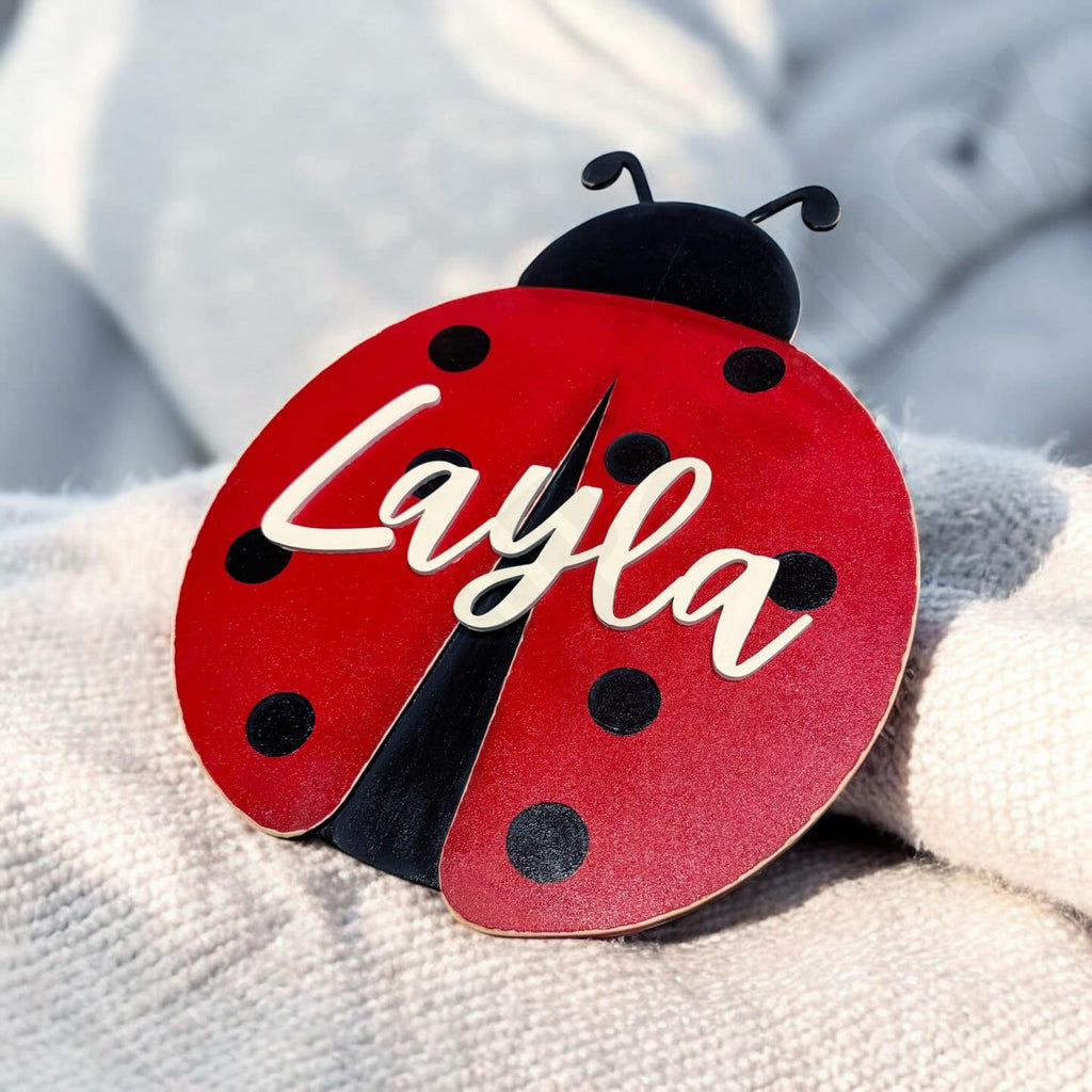 Red ladybug-shaped sign with 'Layla' on a textured surface