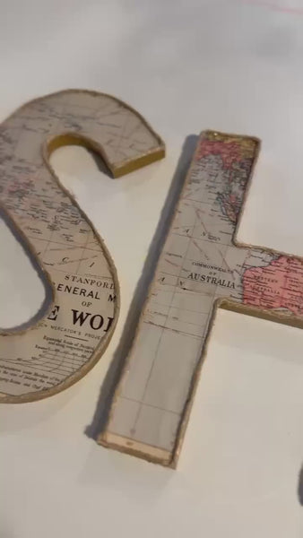 Wooden letters spelling out the name SHANE decorated with a world map across each letter.